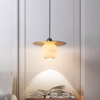 Clérachic Brass and Alabaster Globe Cord Pendant Light lighting an open book and reading glasses on a bedside table.