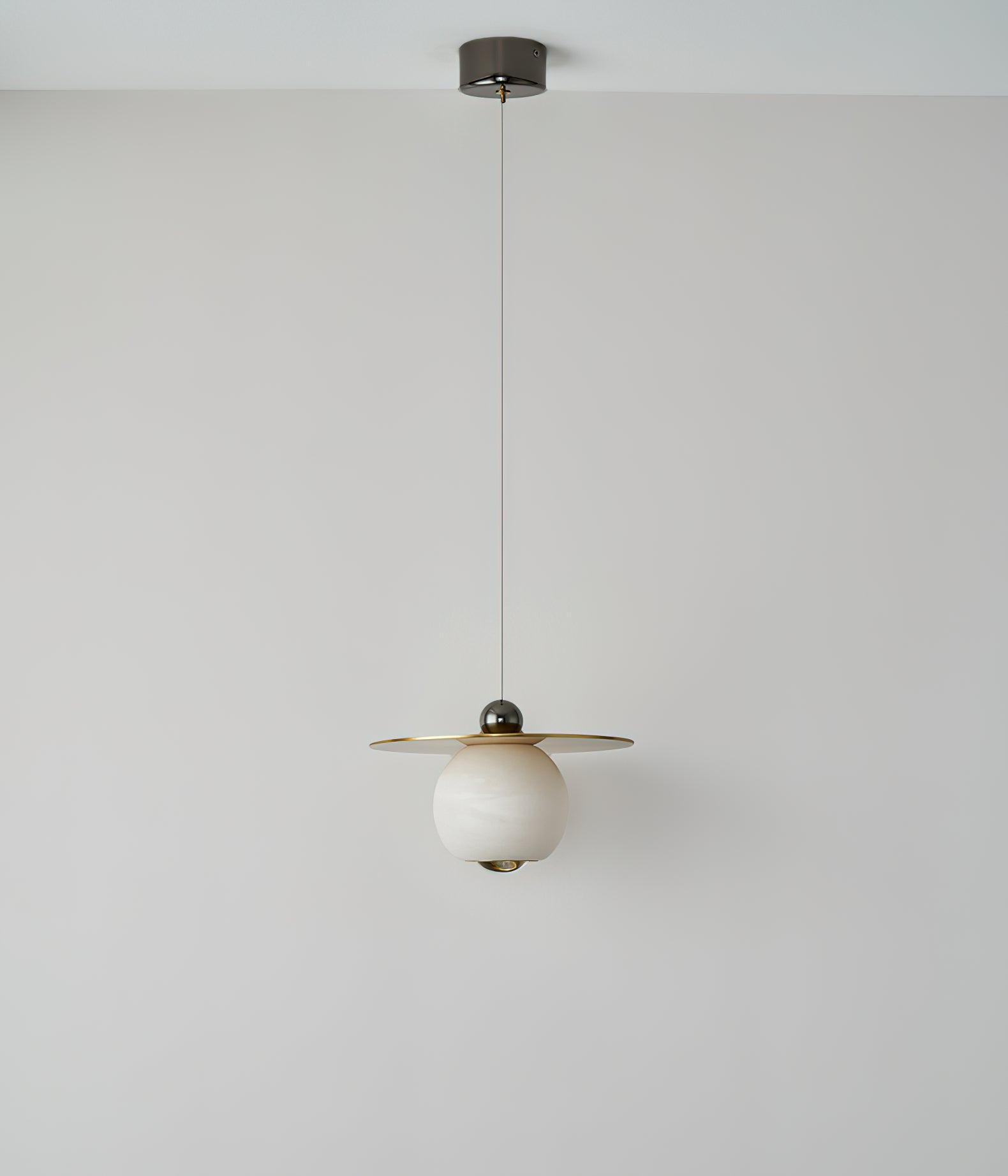 Clérachic Brass and Alabaster Globe Cord Pendant Light at full drop from its round ceiling canopy, switched off.