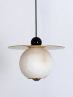 Close study of the Clérachic Brass and Alabaster Globe Cord Pendant Light: black ball, brass disc, veined stone globe.
