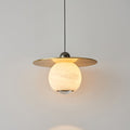 Clérachic Brass and Alabaster Globe Cord Pendant Light lit, warm light bouncing off the underside of the brass disc.