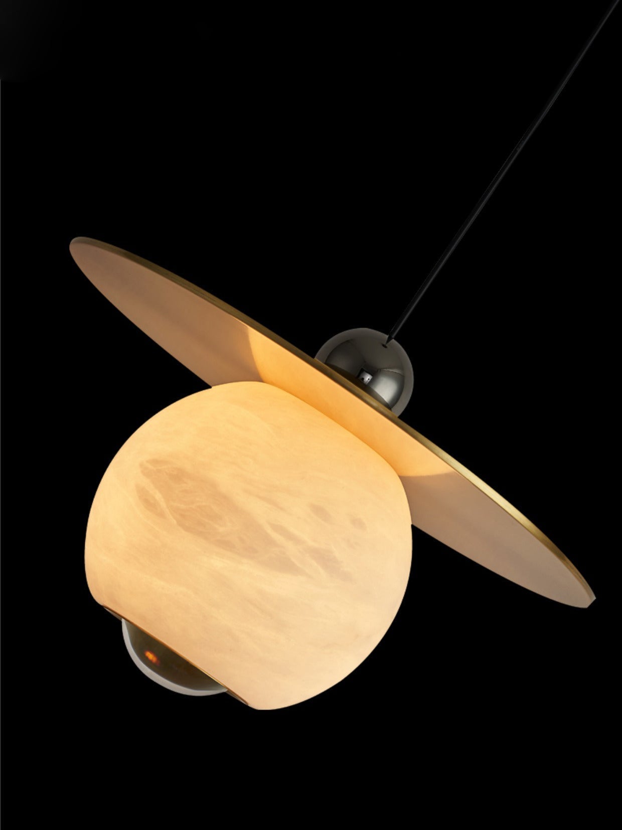 Angled view of the Clérachic Brass and Alabaster Globe Cord Pendant Light on black, brass disc tilted above the lit globe.
