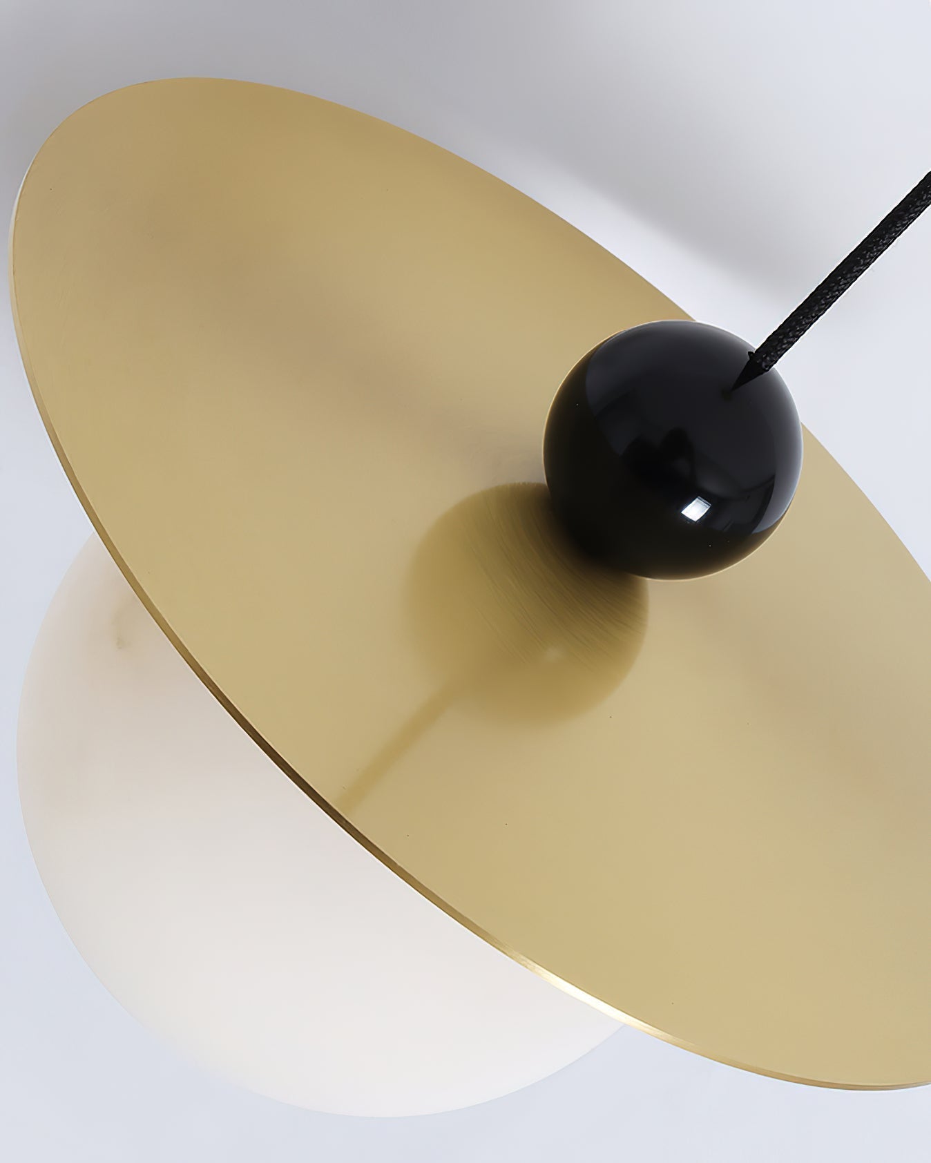 Top detail of the Clérachic Brass and Alabaster Globe Cord Pendant Light, black gloss ball seated on the brass plate.