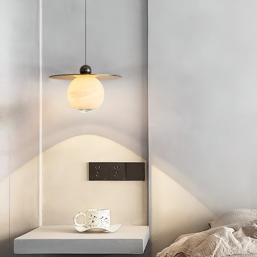 Clérachic Brass and Alabaster Globe Cord Pendant Light lighting a plaster alcove ledge with a speckled ceramic cup.
