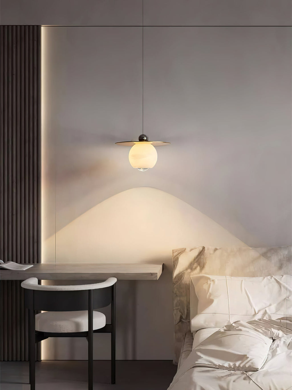 Clérachic Brass and Alabaster Globe Cord Pendant Light over a slim wood desk and black-framed chair beside the bed.