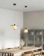 Two Clérachic Brass and Alabaster Globe Cord Pendant Lights hung over an oak dining table with gypsophila in glass.