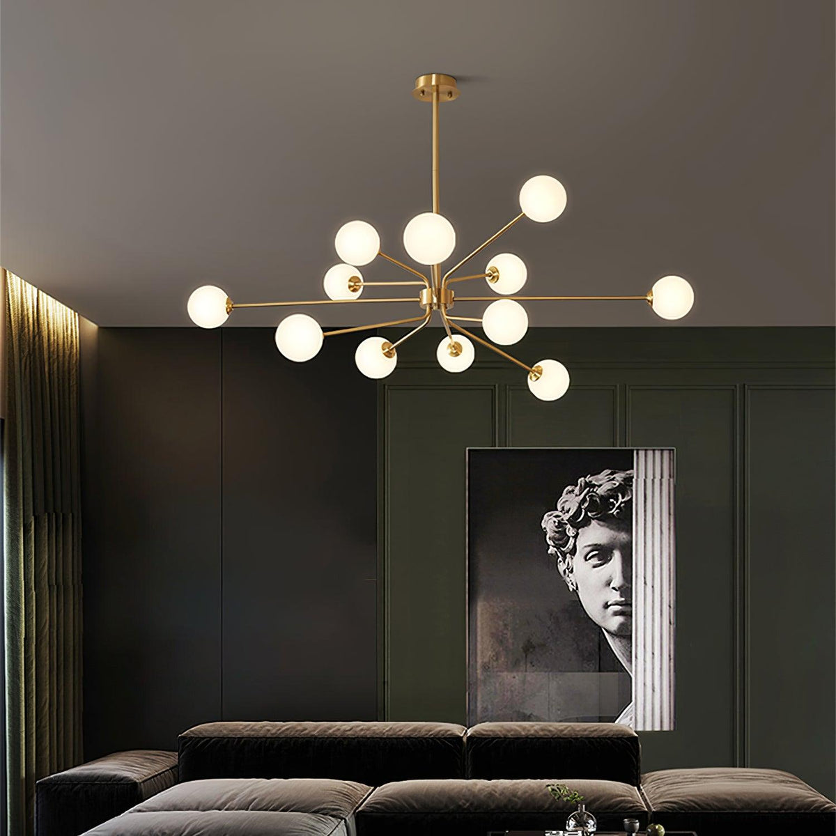 Brass Clérachic chandelier with a dense cluster of white globes above a dark velvet sofa, with a classical bust poster behind.