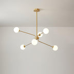 A smaller brass Clérachic chandelier with six white globes on slim arms, hung from a long rod below a pale ceiling.