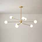 Brass Clérachic chandelier with nine white globes on arms of different lengths, against a plain light wall.
