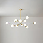Large brass Clérachic chandelier with glowing white globes on many arms, hanging under a light grey ceiling.