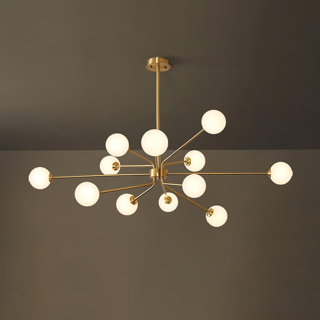 A large brass Clérachic chandelier with a full cluster of glowing white globes, against a dark olive wall and ceiling.
