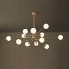 A large brass Clérachic chandelier with a full cluster of glowing white globes, against a dark olive wall and ceiling.