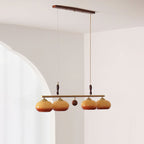 Four-head Clérachic bar pendant with a wooden ball at its centre, hung from a wooden ceiling plate in front of an arched white wall.