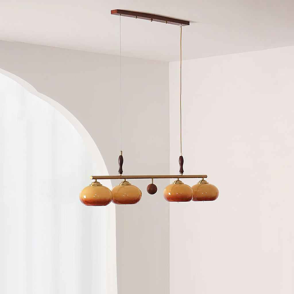 Four amber glass shades split in pairs by a small wooden ball on this Clérachic pendant, seen in a room with an arched opening.