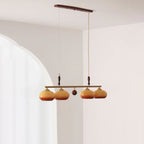 Four amber glass shades split in pairs by a small wooden ball on this Clérachic pendant, seen in a room with an arched opening.