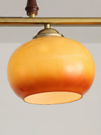 One round amber glass shade of this Clérachic pendant, with a brass cap and bar above and a wooden grip, its rim open at the base.