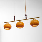 Tilted view of the Clérachic bar pendant showing the inside of three amber shades with a white lining and brass caps.
