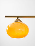 Round amber glass shade with a brass cap, from the Clérachic bar pendant, shown on its own against a pale background.