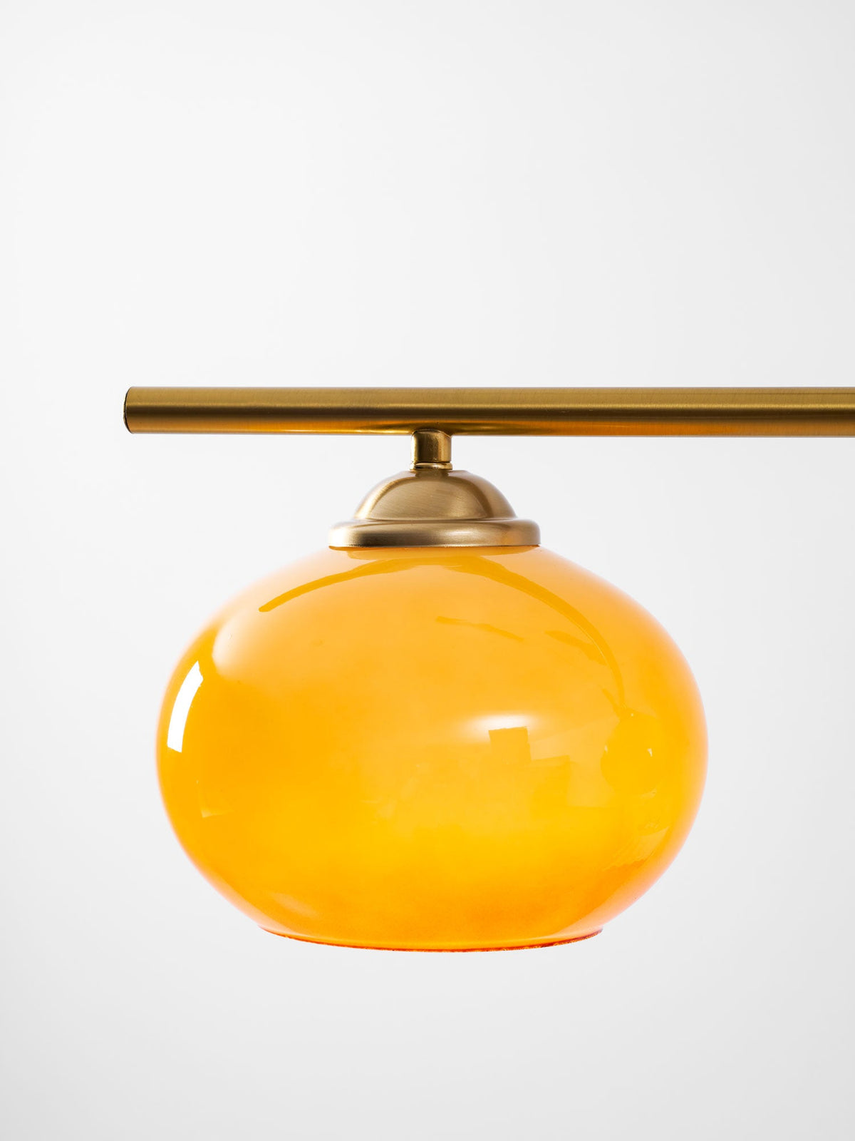 Round amber glass shade with a brass cap, from the Clérachic bar pendant, shown on its own against a pale background.