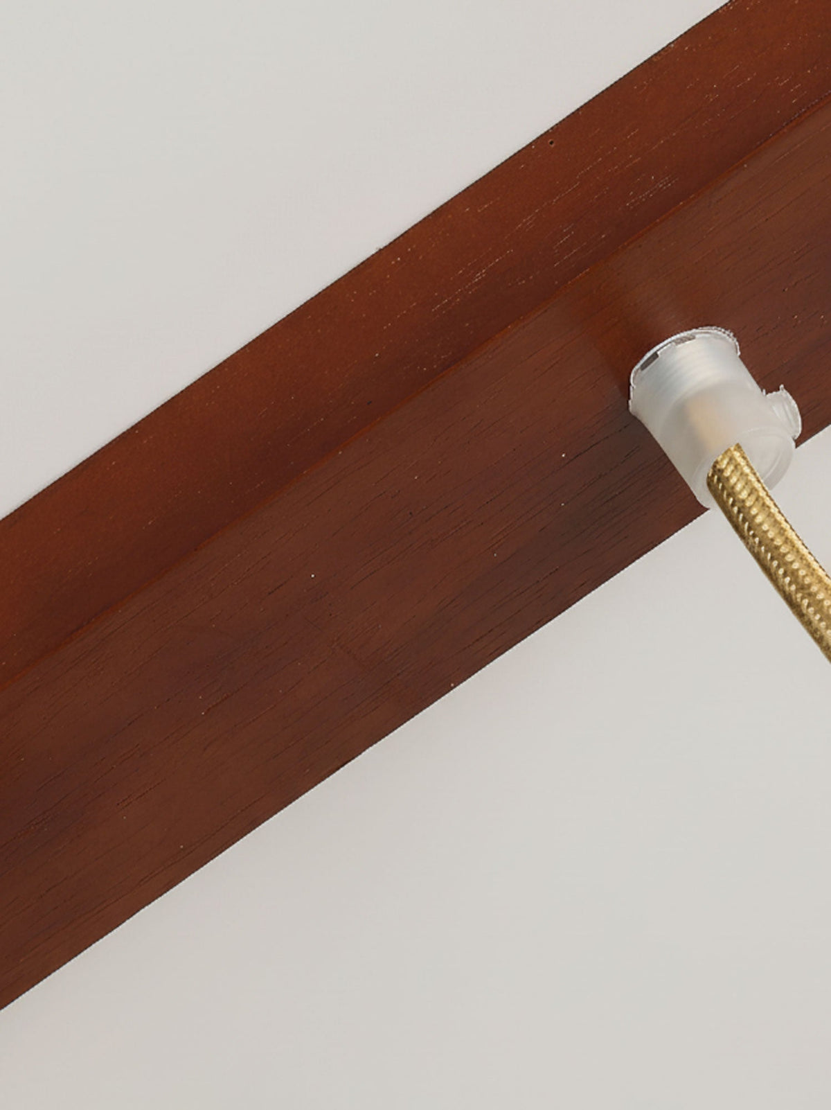 Close view of the wooden ceiling bar of this Clérachic pendant, where the braided gold cord enters through a frosted cable gland.