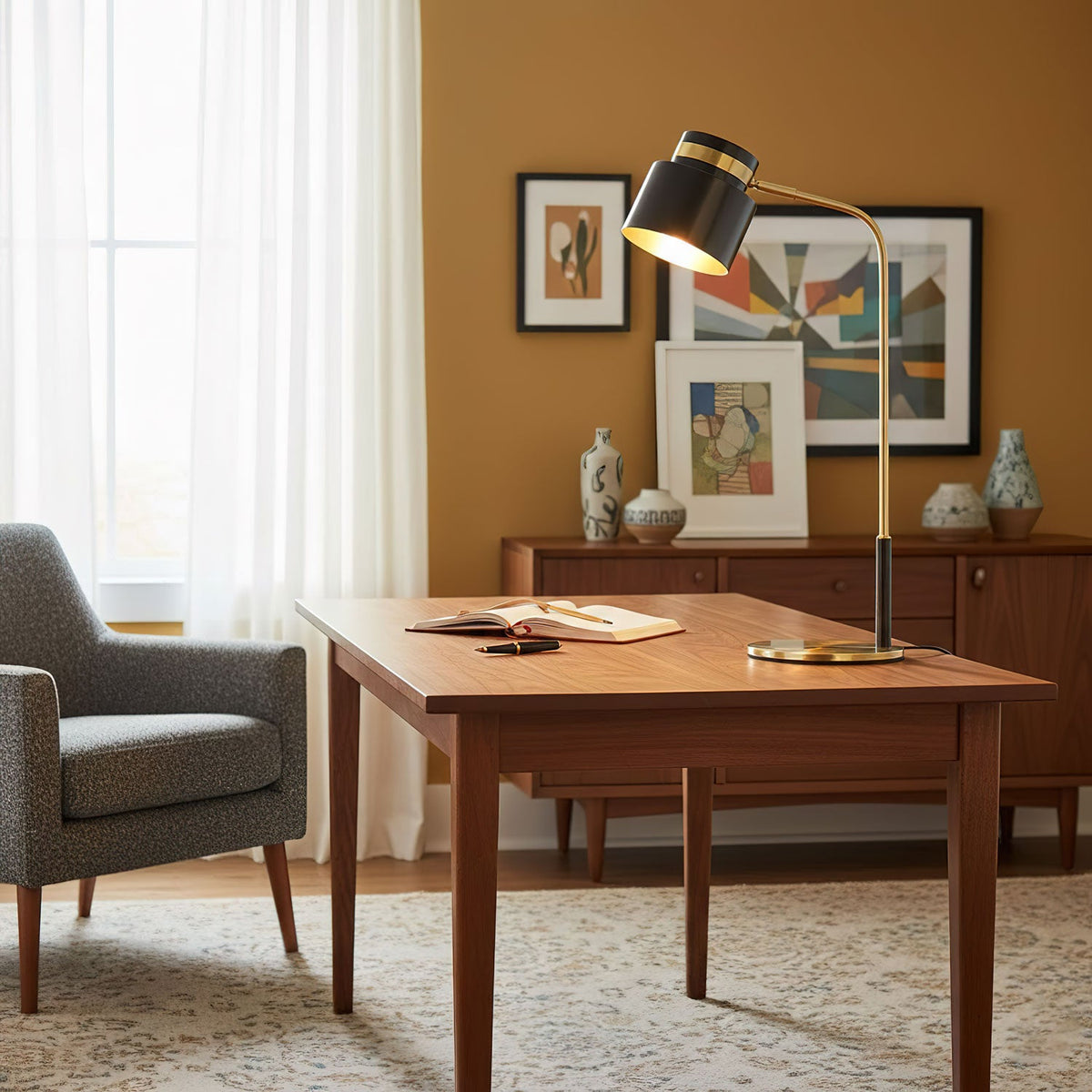 A Clérachic desk lamp on a walnut-toned table in a warm room with an ochre wall, framed art and a grey armchair.