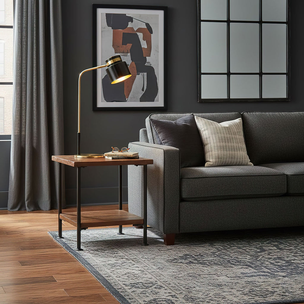 Beside a charcoal sofa, a Clérachic table lamp lights a small wood side table below abstract wall art and a grid mirror.