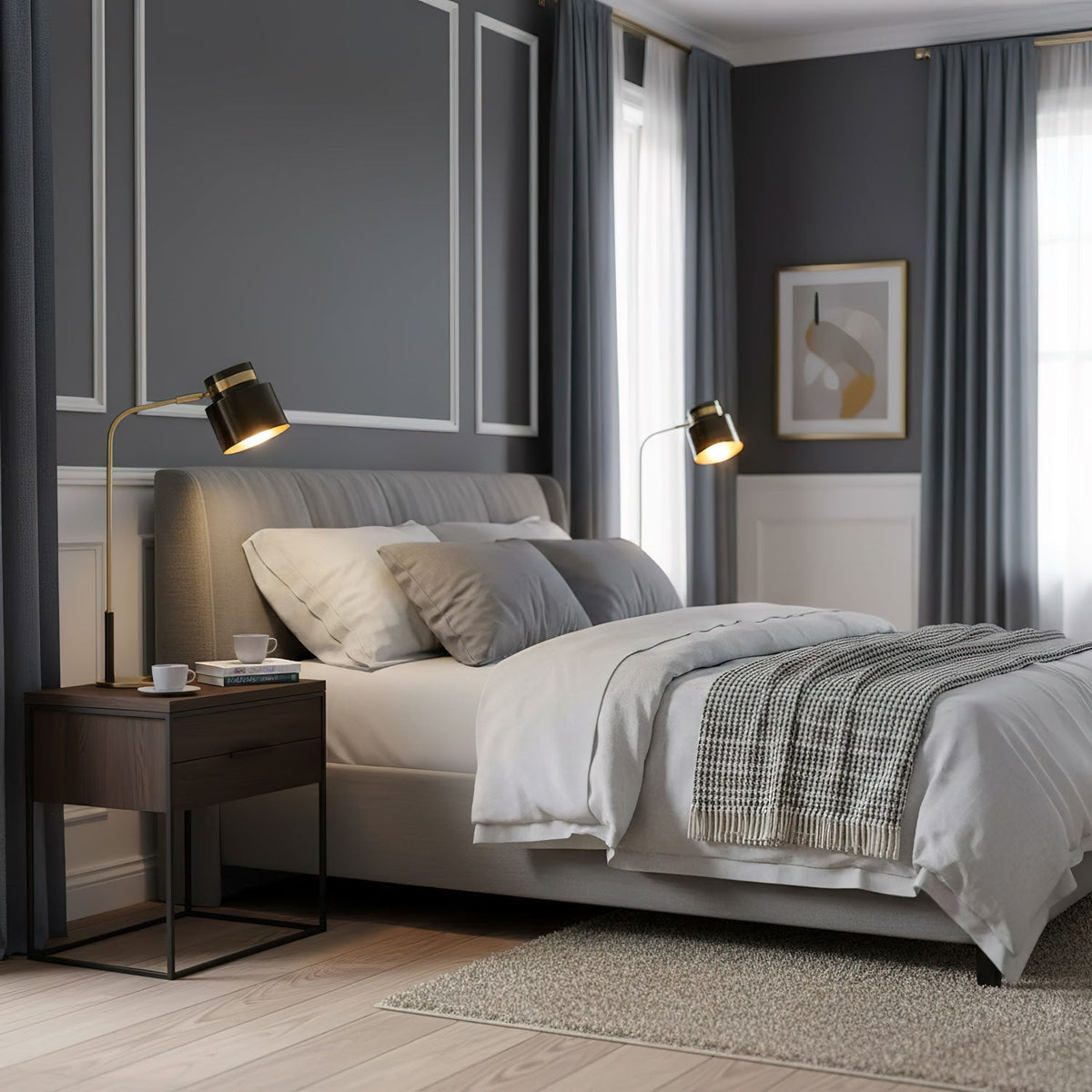 A Clérachic lamp lit on a dark bedside table, with a grey upholstered bed and navy curtains in the room beyond.