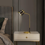 A Clérachic lamp on a cream bedside cabinet with a single drawer, next to a houndstooth headboard in a dark grey room.