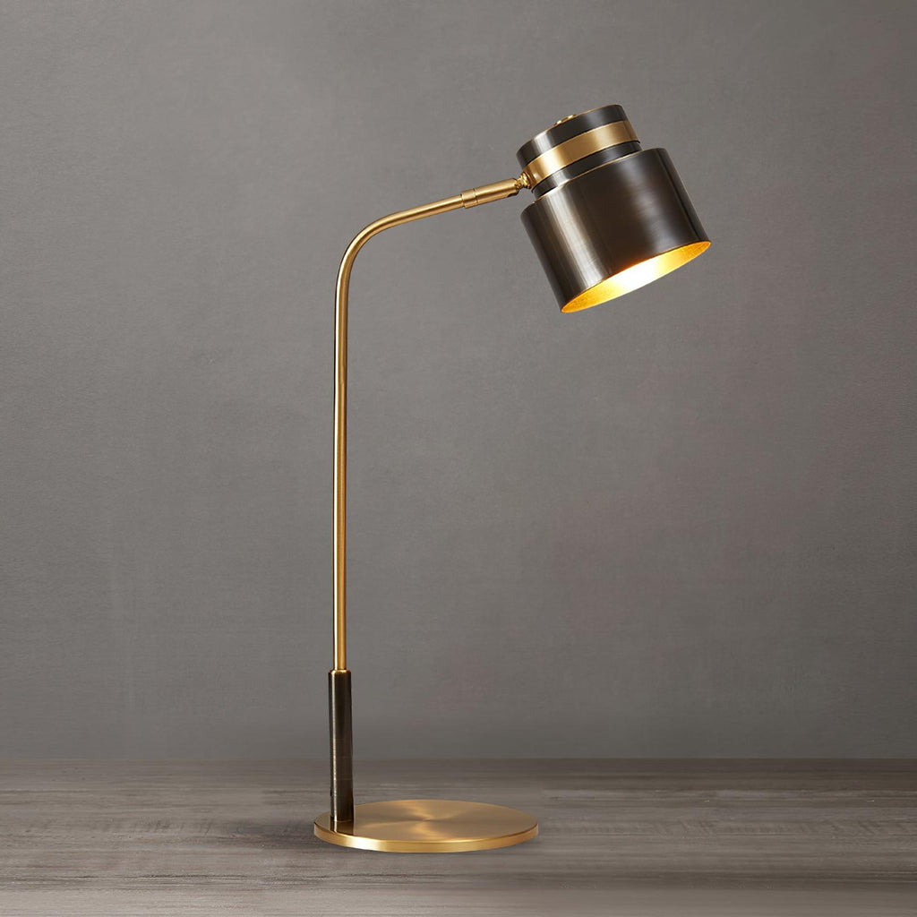 This Clérachic table lamp seen from a slightly different angle on a grey backdrop, its gold-lined shade tilted forward.
