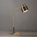 This Clérachic table lamp seen from a slightly different angle on a grey backdrop, its gold-lined shade tilted forward.