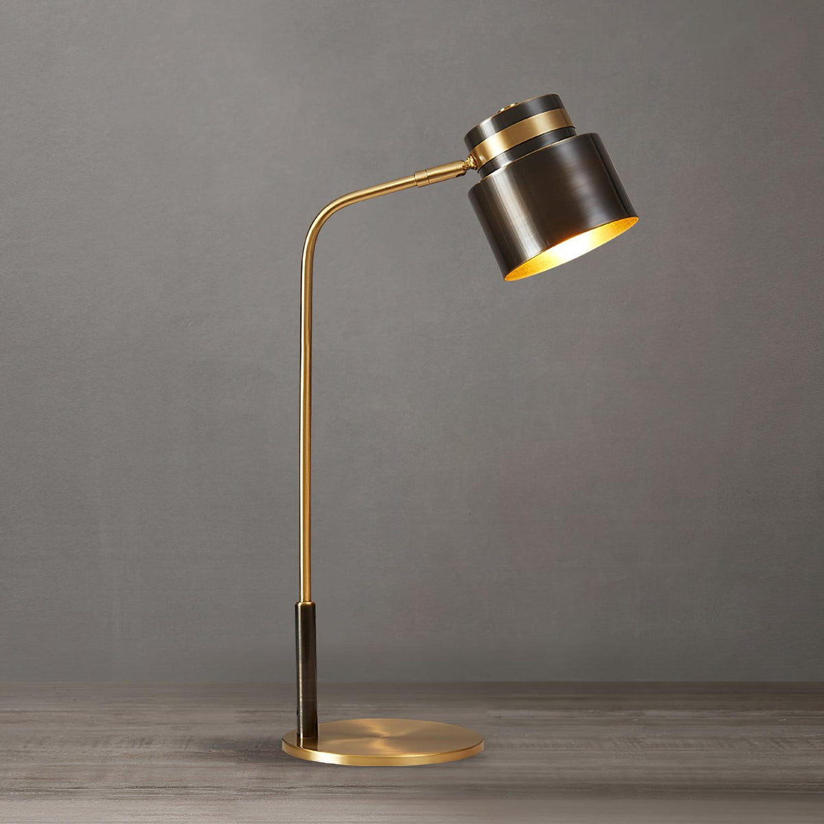 This Clérachic table lamp seen from a slightly different angle on a grey backdrop, its gold-lined shade tilted forward.
