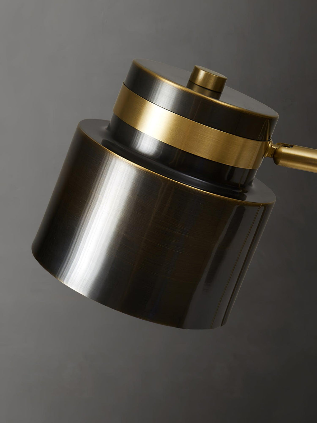 Close view of the dark metal shade and brass band on this Clérachic table lamp, with the cap button on top.