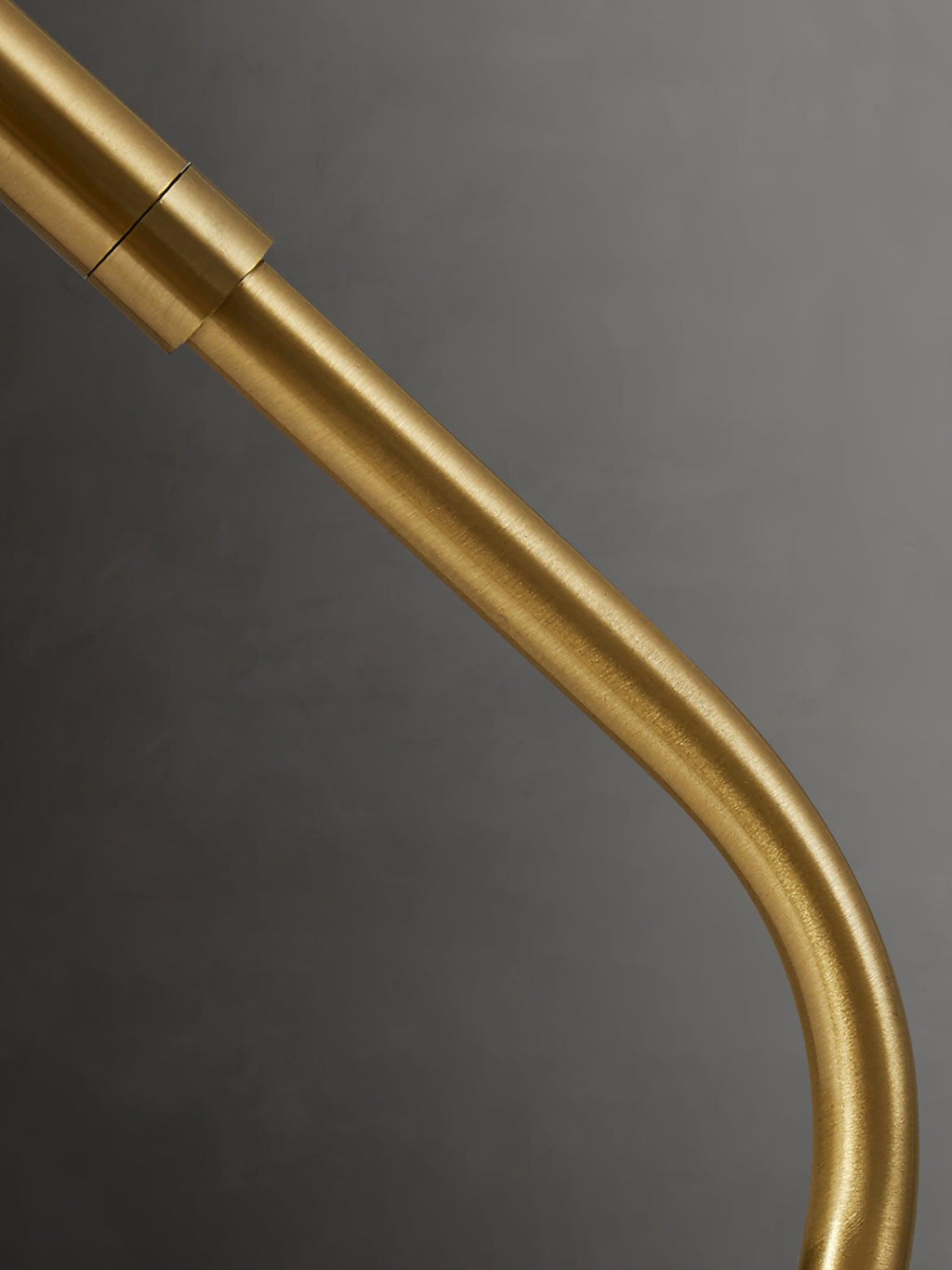 Close view of the curved brass arm and its jointed collar on this Clérachic table lamp.