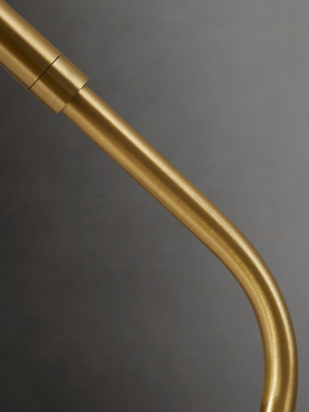 Close view of the curved brass arm and its jointed collar on this Clérachic table lamp.