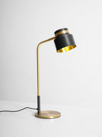This Clérachic table lamp on a pale backdrop with its arm leaning to the right and the shade tipped down.