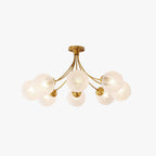 Brass semi-flush ceiling light with rippled glass globes on curved arms, lit warm, on a plain white backdrop, from Clérachic.