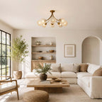 Clérachic brass ceiling light with glass globes in a bright living room with a sectional sofa, built-in shelves and a potted olive.