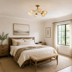 Clérachic brass ceiling light with rippled globes in a bedroom with a wood-framed bed, a woven bench and a landscape print.