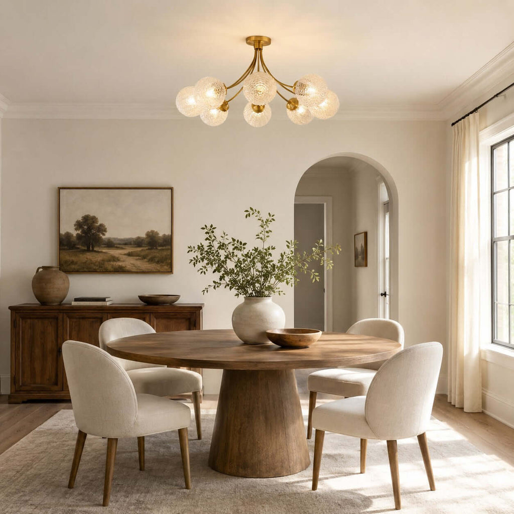 Clérachic glass-globe ceiling light above a round pedestal table with cream chairs, in a room with an arched doorway.