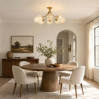 Clérachic glass-globe ceiling light above a round pedestal table with cream chairs, in a room with an arched doorway.