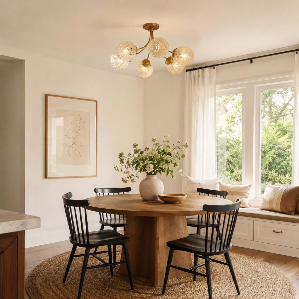 Clérachic ceiling light with rippled glass globes above a round wooden table and black spindle chairs, beside a window seat.