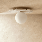 A terrazzo-disc ceiling light with an opal glass globe is shown unlit against a plain plaster ceiling, Clérachic hero shot.