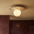 A closer crop shows the lit terrazzo ceiling light against burgundy tile and a plaster archway, Clérachic detail shot.