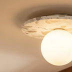 A close-up on the terrazzo disc's flecked pattern and glowing opal globe against a plain ceiling, Clérachic detail shot.