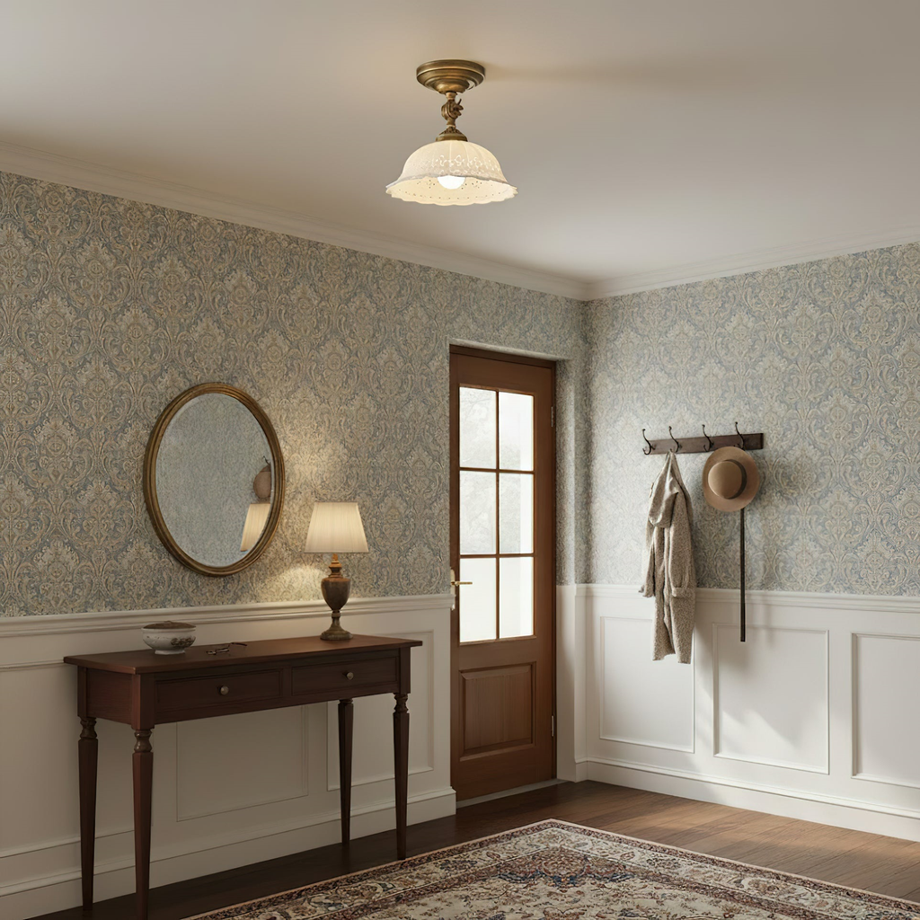 A Clérachic ceramic dome light lit above an entrance hall with patterned wallpaper, a dark wood console table and an oval mirror.