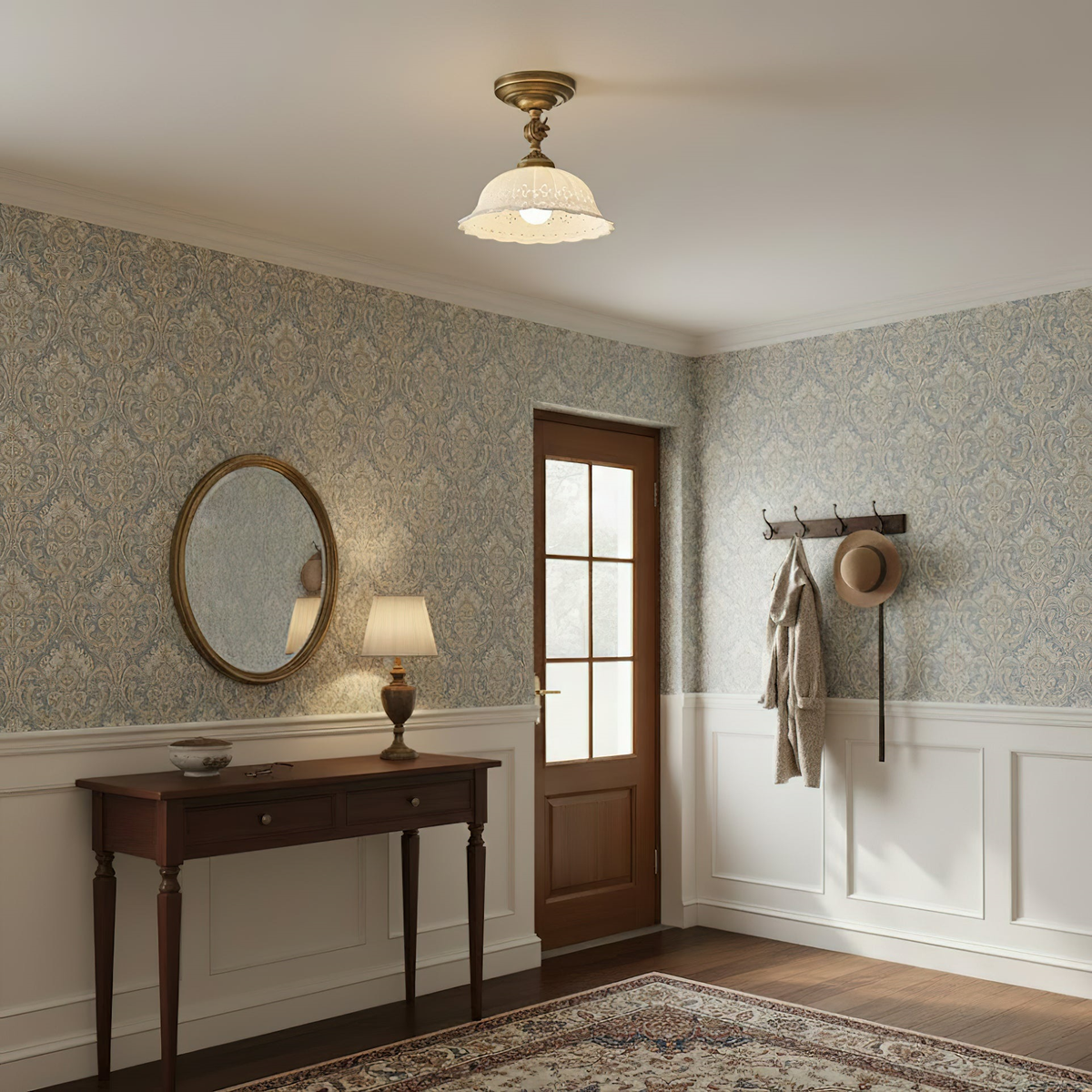 A Clérachic ceramic dome light lit above an entrance hall with patterned wallpaper, a dark wood console table and an oval mirror.