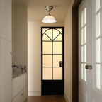 Brass-armed ceramic ceiling light from Clérachic in a doorway, with a black-framed glazed door and a frosted pane behind it.