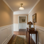 Clérachic ceramic dome light hanging in a long hallway with warm beige walls, white panelling, a runner rug and a wooden console.