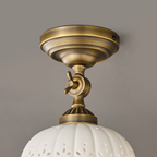 Close view of the layered brass canopy and the wing-nut swivel joint above the ceramic dome of this Clérachic ceiling light.