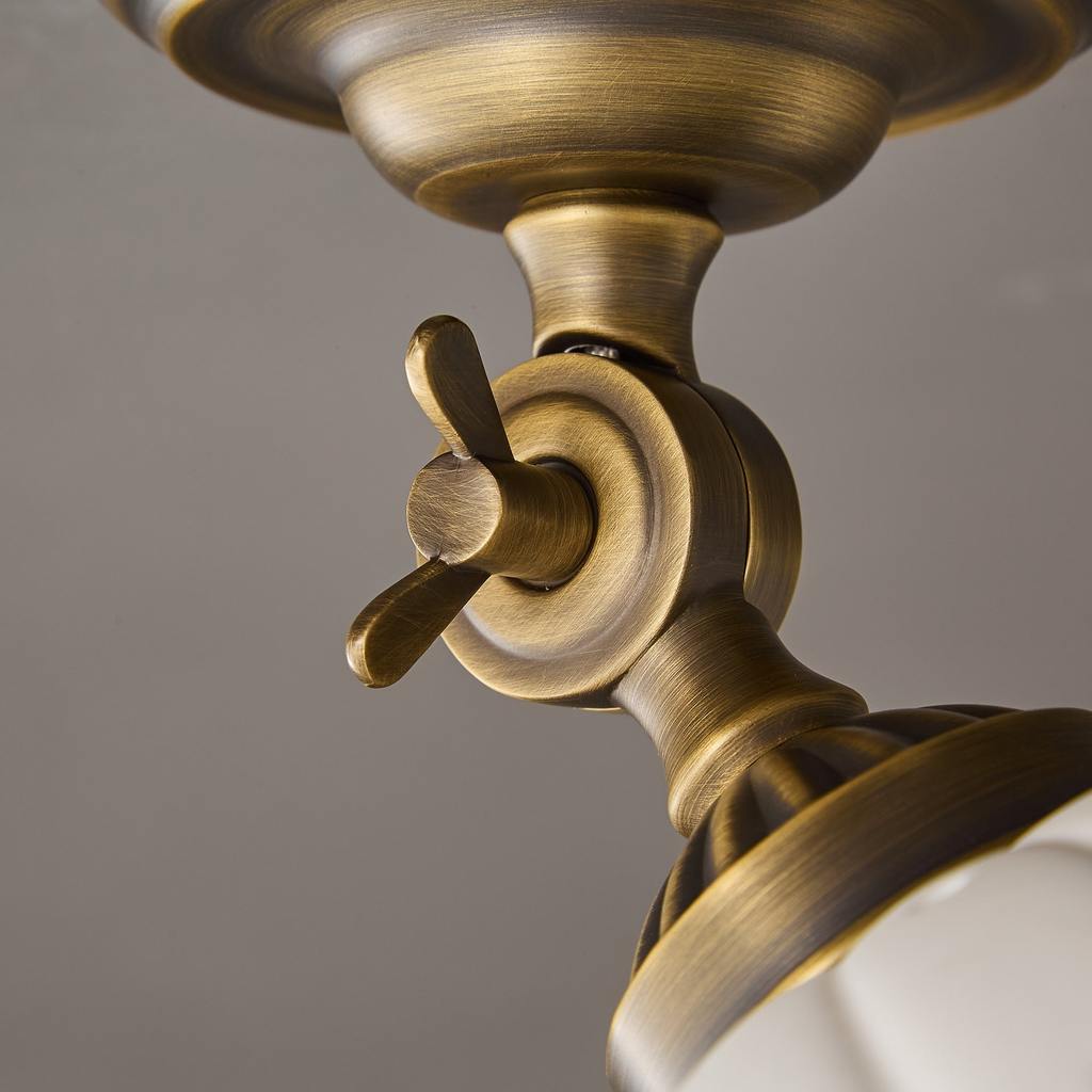 Extreme close view of the brass wing-nut swivel joint and ribbed collar on this Clérachic ceiling light, with the ceramic dome below.