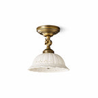 Slightly angled view of a Clérachic antique brass ceiling light with a fluted white ceramic dome and a pierced scalloped edge, on white.